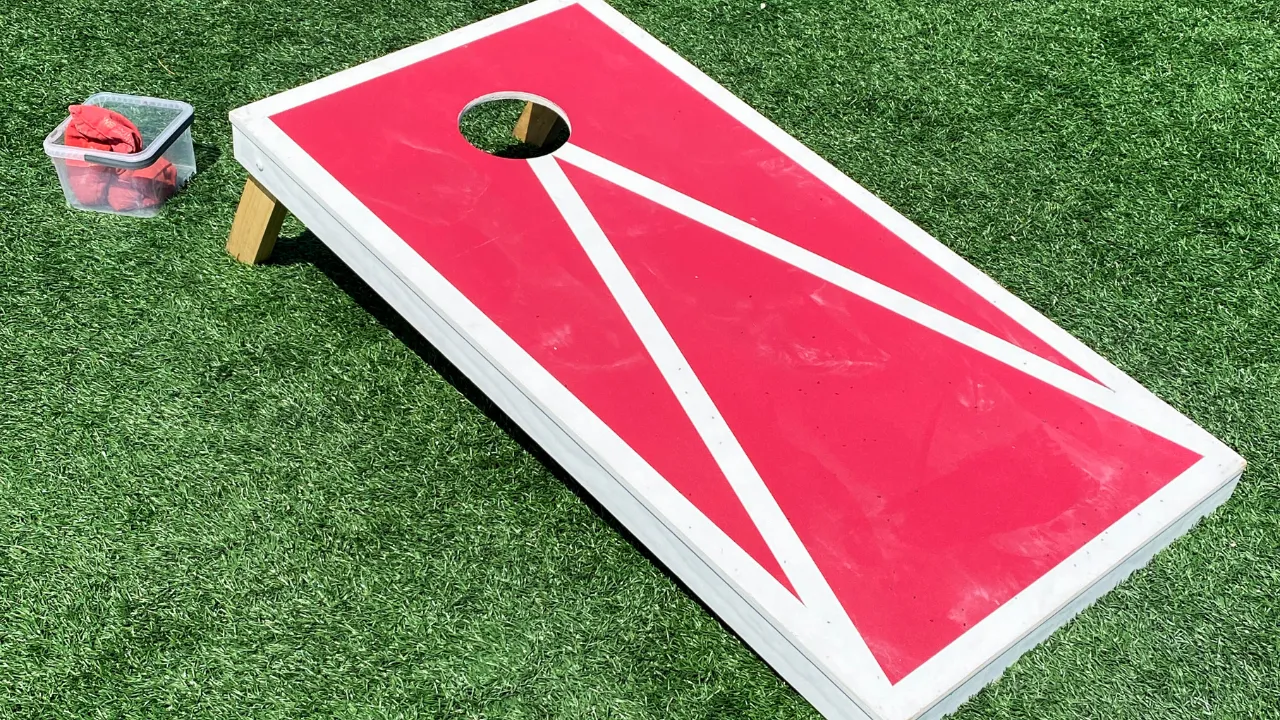Empty red cornhole board on artificial in casual cornhole Austin style setup.